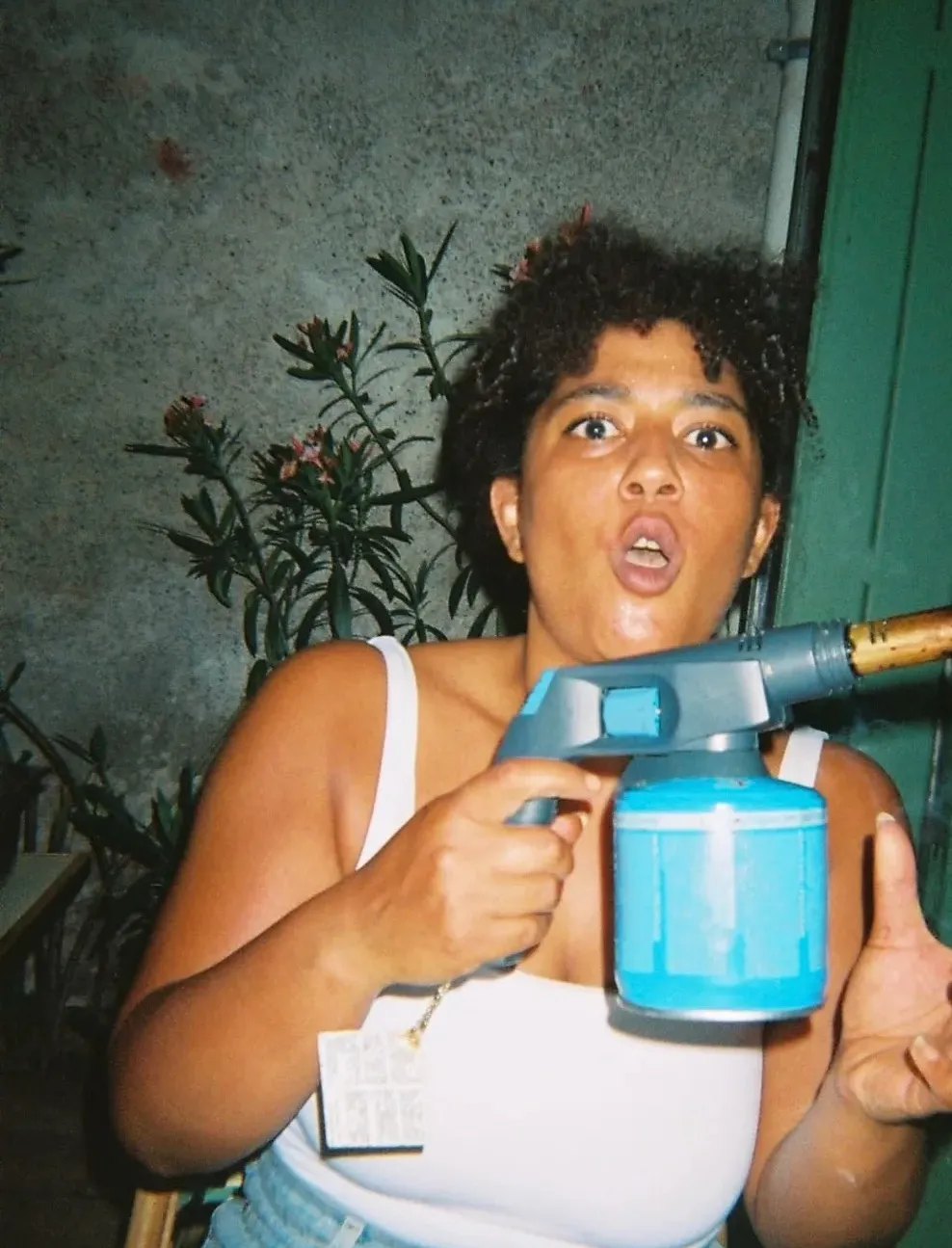 Une invitée prend la pose avec un chalumeau de cuisine, devant les lauriers-roses de la terrasse