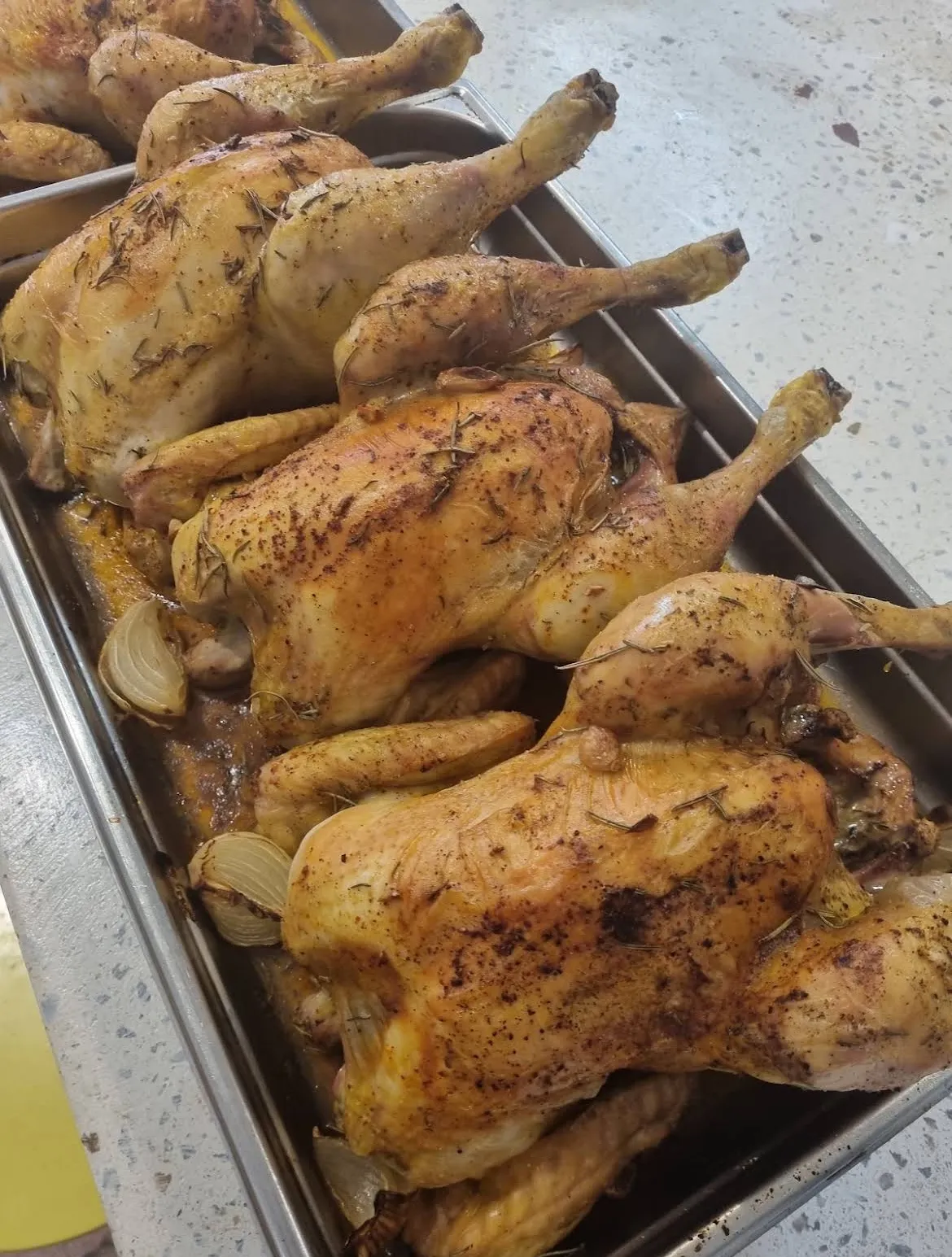 En cuisine chez Mammouth, un grand plat de poulets rôtis aux herbes et à l’ail, tout juste sortis du four