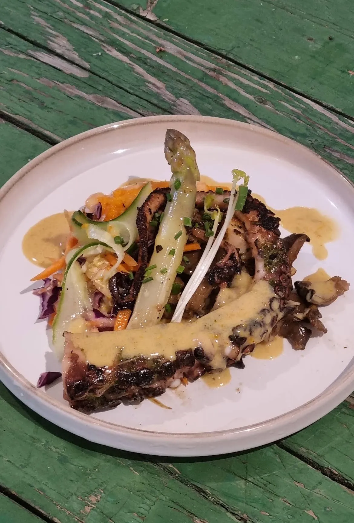 Poulpe grillé, asperge et légumes dans une assiette sur la table verte