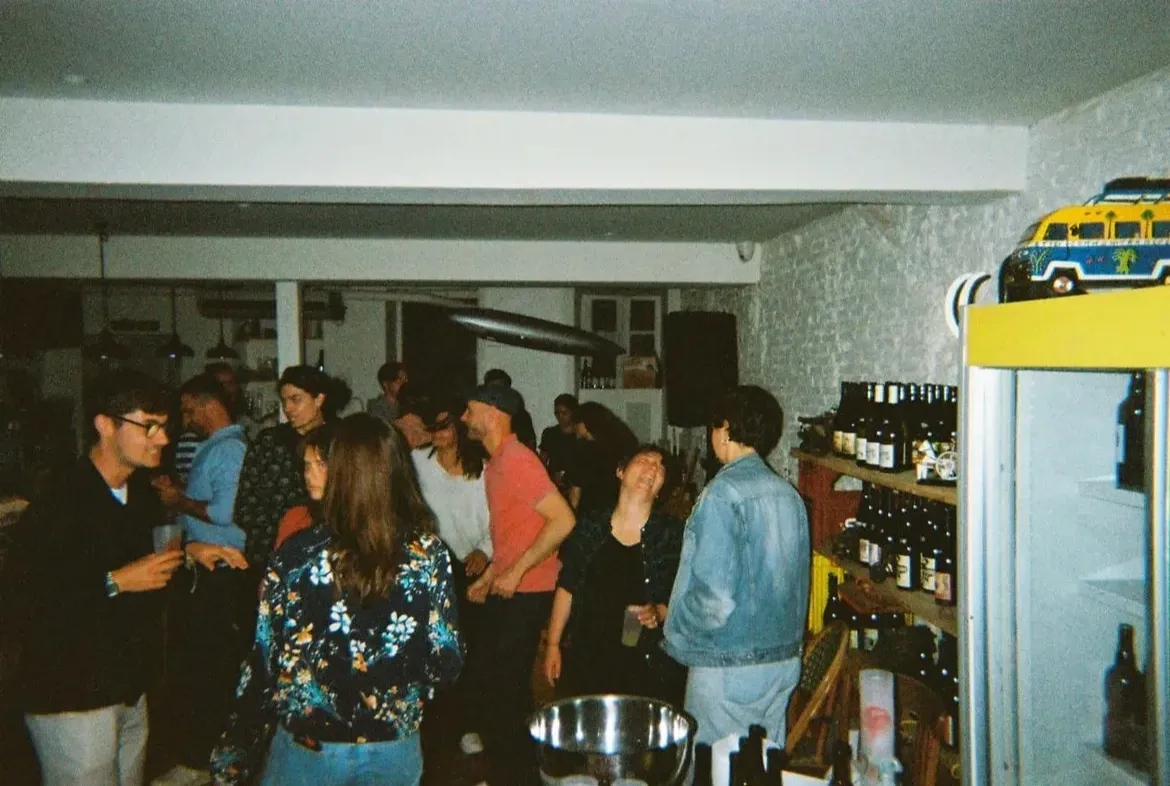 La salle de Mammouth pleine d’invités pendant une soirée, entre les étagères de bouteilles et le réfrigérateur
