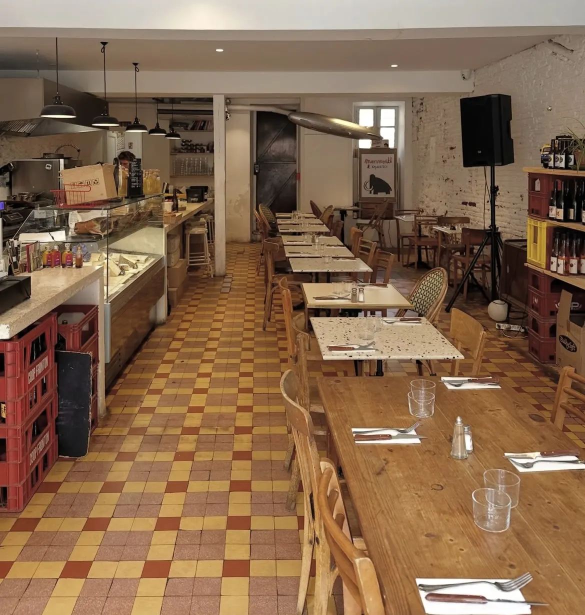 La salle de Mammouth, ses tables en terrazzo, ses chaises en bois et son sol à carreaux