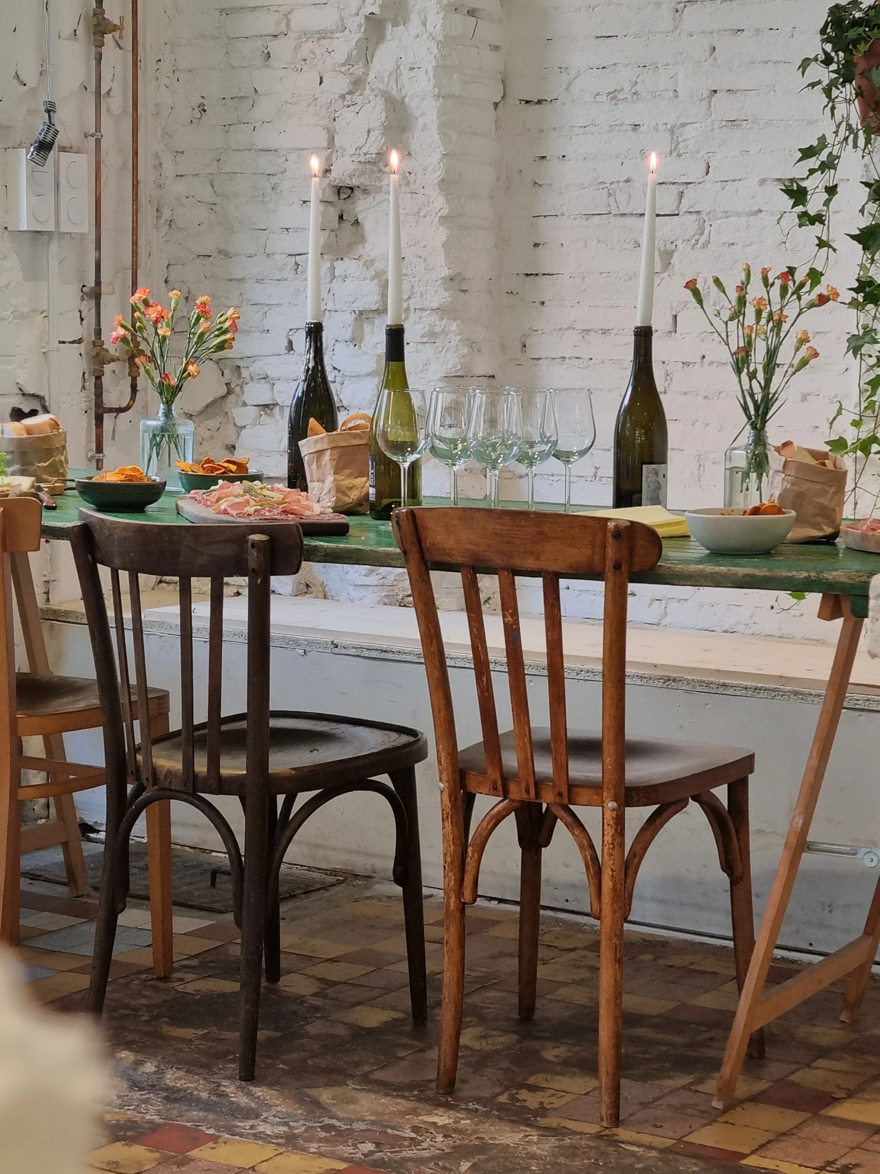 La salle de Mammouth : table verte dressée, bougies, fleurs et chaises en bois