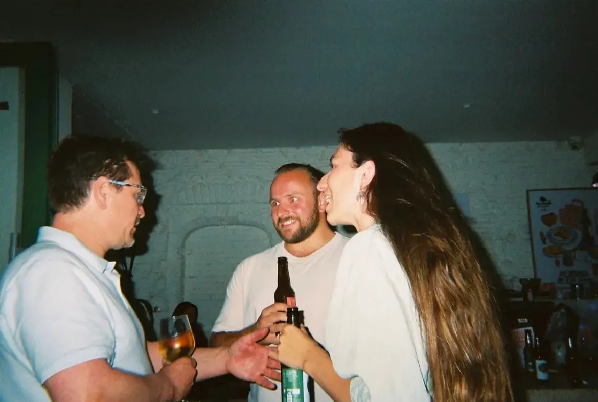 Trois invités trinquent dans la salle de Mammouth, bière et vin blanc à la main